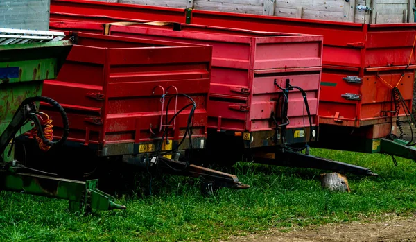 Červené Přívěsy Používané Pro Traktory Zaparkované Řadě Zeleném Poli Kvalitní — Stock fotografie