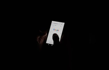 İnternette arama yapmak üzere olan bir cep telefonunu tutan eller. Siyah arka plan. Yüksek kalite fotoğraf