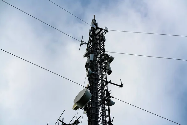 Large cellular communications tower with arrays, antennas and dishes for providing mobile connections as well as both 4G and 5G internet.