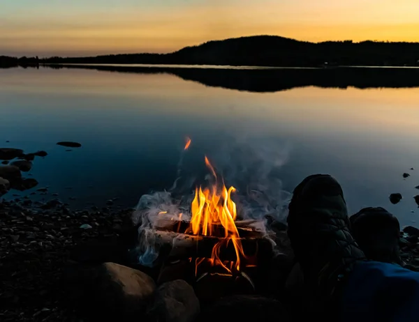 徒步旅行者的靴子在湖边篝火边休息 是的高质量的照片 — 图库照片