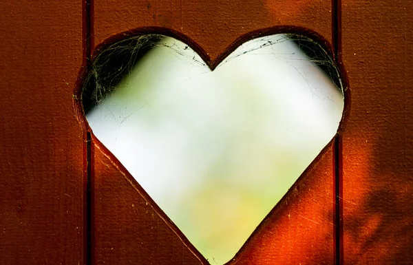 Heart shape cut out of a red wooden plank door on an outhouse toilet. close up. . High quality photo — Stock Image Heart Shape Cut Out Red Wooden Plank Door Outhouse Toilet Stock Picture