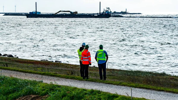 身穿反光背心和硬礼帽的检查员负责监督将连接丹麦和德国的法哈曼海峡隧道项目的新海港的建造 是的高质量的照片 — 图库照片