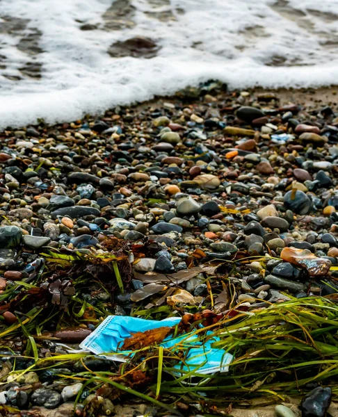 Used face mask from the corona virus pandemic, washed ashore as garbage on a beach. . High quality photo