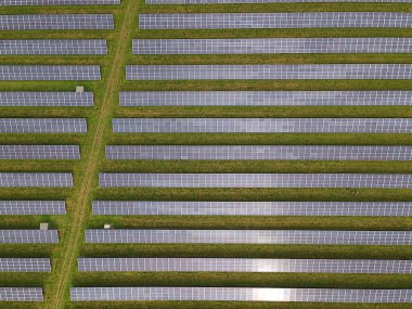 Çim tarlasında uzun sıra modern güneş panelleri olan güneş enerjisi çiftliği. Hava görüntüsü. - Evet. Yüksek kalite fotoğraf