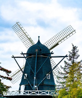 Eski günlerde un öğütmek için kullanılan eski siyah ahşap değirmen. Arka planda bulutlar ve mavi gökyüzü var. - Evet. Yüksek kalite fotoğraf