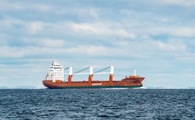 Büyük vinçleri olan kırmızı kargo gemisi denize açılıyor. Yüksek kalite fotoğraf