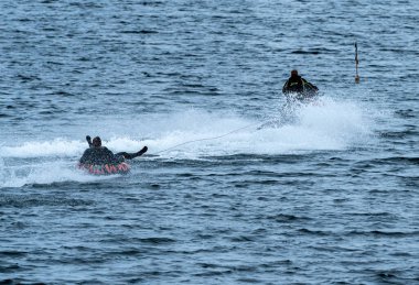 Şişme yüzüklü bir adam sahile yakın bir jet ski 'nin arkasında çekiliyor. - Evet. Yüksek kalite fotoğraf