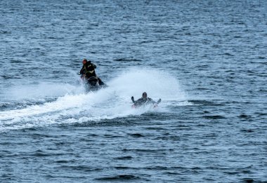 Şişme yüzüklü bir adam sahile yakın bir jet ski 'nin arkasında çekiliyor. - Evet. Yüksek kalite fotoğraf