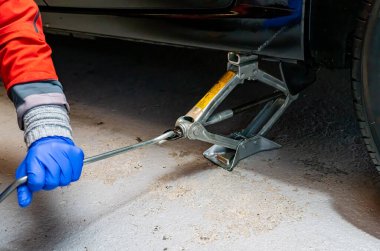Lastik değiştirirken acil durum krikosunda araba kaldıran birinin kolu ve eli. - Evet. Yüksek kalite fotoğraf