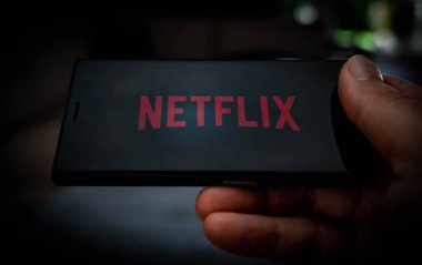Netflix logosu olan bir cep telefonunu ekranda göstererek yayın hizmetlerini resmetmek. Yüksek kalite fotoğraf