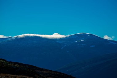 Bulutlar sabah ışığında bir dağın zirvesine doğru hareket ediyor. - Evet. Yüksek kalite fotoğraf
