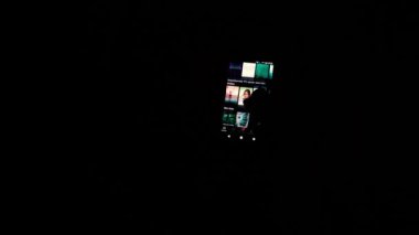 Karanlıkta cep telefonunda Netflix 'te başlıkları karıştıran parmaklar.