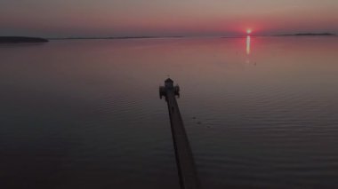 Gün batımında deniz kenarındaki uzun ahşap iskelenin havadan görünüşü..