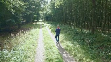 Orman yolunda ağaçların fotoğraflarını çeken bir erkek fotoğrafçı..