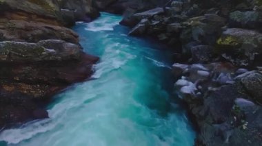 Buz gibi buzul suyu donmuş kayalıklardan nehrin aşağısına doğru ilerliyor. 4K video