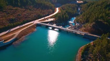 Mavi su deposu olan bir dağ vadisinde hidroelektrik barajı. 4K hava görüntüsü.