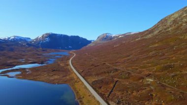Sonbaharda dağlık bölgede engebeli arazi ve göllerden geçen dağ geçidi yolu. Hava videosu.