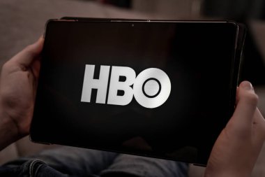 Siyah ekranda HBO logosu olan tableti tutan eller. Yüzeyin derinliği. Yüksek kalite fotoğraf