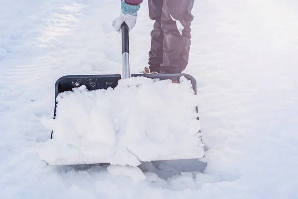 Close up of a person clearing snow from the sidewalk with a snow shovel. Shallow depth of field. High quality photo