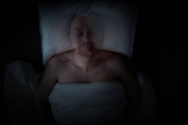 Huzursuz bir uykuda olan bir adam kötü rüyalar görüyor. Düşük ışıkta hareket bulanıklığı. Yüksek kalite fotoğraf