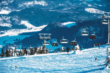 Sandalye kaldıran insanların olduğu bir kayak merkezini görüntüle.