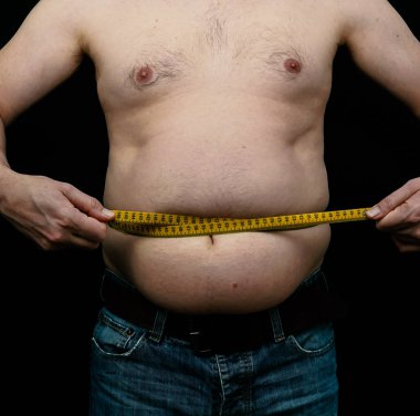 Şişman adam göbeğini ölçüyor. Siyah arka planda izole edilmiş. Yüksek kalite fotoğraf