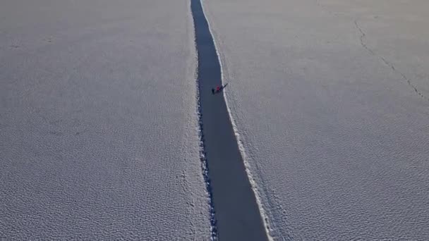 人々は晴れた寒い冬の日に凍った湖でスケートをします トップダウンビュー — ストック動画