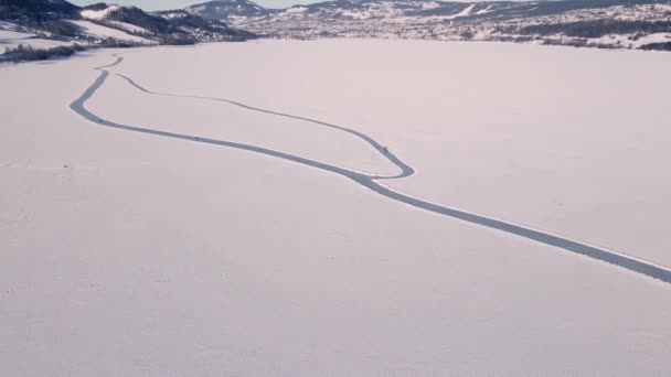人々に沿ってスケートと大規模な凍結湖で氷のスケート道路 トップダウン空中ビデオ — ストック動画