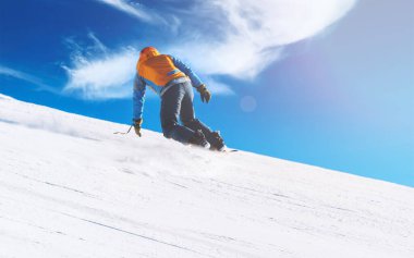 Güneşli bir günde açık mavi gökyüzüyle dik bir yamaçtan kayan snowboardcu. Yüksek kalite fotoğraf