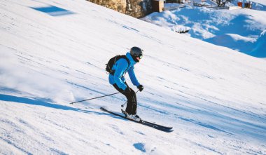 Tepe aşağı kayakçı parlak kış güneşinde dik bir yamaçtan hızla iniyor. Yüksek kalite fotoğraf