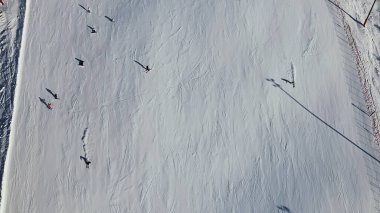 Top down view of skiers riding down an alpine skiing slope on a sunny winters day. High quality photo