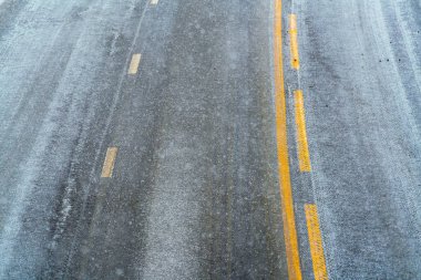 Kar ve buzla kaplı yol asfaltının görüntüsünü kapat.