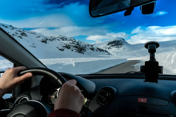 雪に覆われた山道を渡す車の運転のステアリングホイールに手 高品質の写真 ストック画像