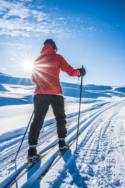 Jovem mulher cross country esqui em um dia ensolarado em montanhas cobertas de neve. — Fotografia de Stock