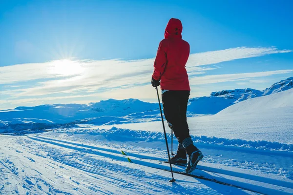Jovem mulher cross country esqui em um dia ensolarado em montanhas cobertas de neve. — Fotografia de Stock