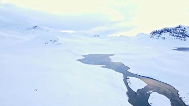 从空中俯瞰穿越荒芜积雪覆盖的冻土带和山脉的北极河流 — 图库视频影像