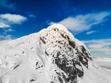 Bulutlar ve mavi gökyüzüyle karla kaplı dağ zirvesinin panoramik görüntüsü. Norveç 'teki Bitihorn Dağı. Yüksek kalite fotoğraf