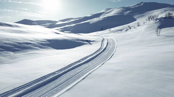 Pista de esquí de fondo corriendo a través de impresionantes montañas cubiertas de nieve. Imágenes De Stock Sin Royalties Gratis