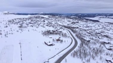 Bulutlu bir kış gününde, Beitostlen köyü ve kayak merkezinin sıcacık kütük kulübeleriyle panorama.