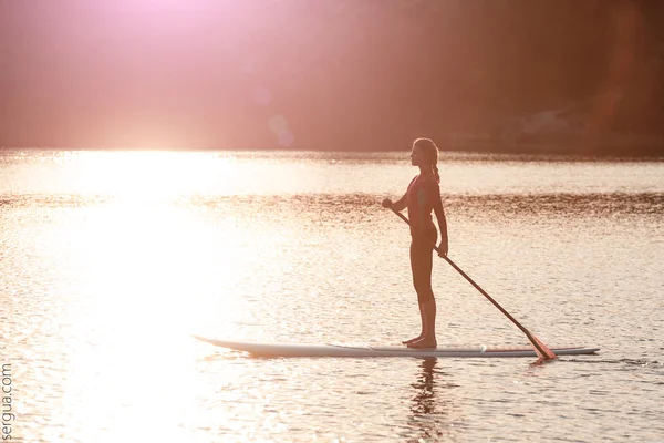 Silhouette de jeune fille pagaie embarquement au coucher du soleil01 — Photo