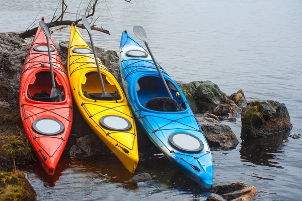 Kayaks de fibra de vidrio de colores que yacen en la costa rocosa01 — Foto de Stock