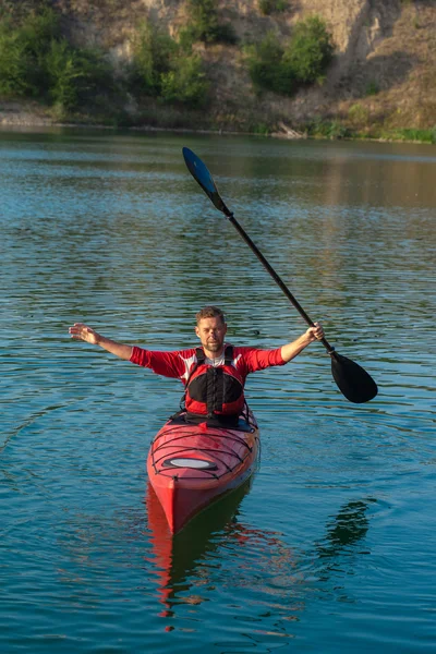Человек плавает на каяке и держит весло над головой — стоковое фото