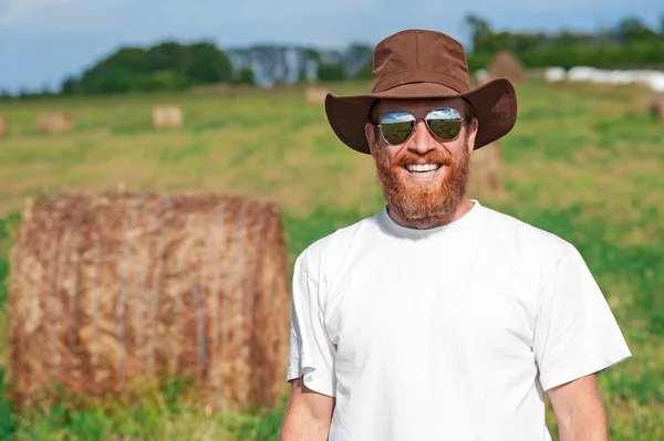 Retrato de fazendeiro sorridente no campo de feno — Fotografia de Stock