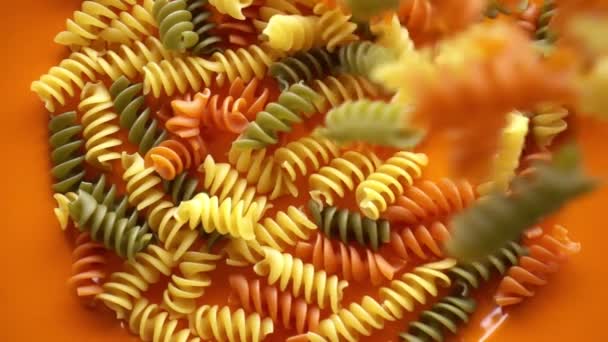 Raw flerfärgad makaroner pasta faller på plattan, slow motion — Stockvideo