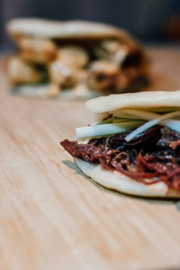 Füzyon yiyecek ördek bao ve bao İspanyol kızarmış kalamar ve kimchi mayonezli bambu masasında.