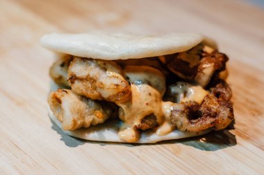 Bambu masasında İspanyol usulü kızarmış kalamar ve kimchi mayonezli bao.
