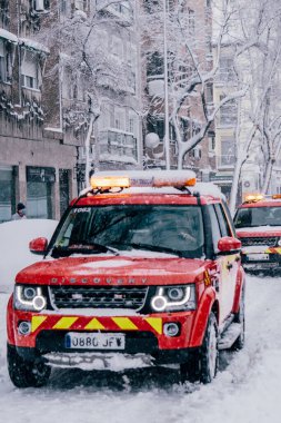 Madrid, İspanya - Ocak 2021: Filomena Fırtınası nedeniyle iki itfaiye aracı caddenin ortasında. Kırmızı araba..