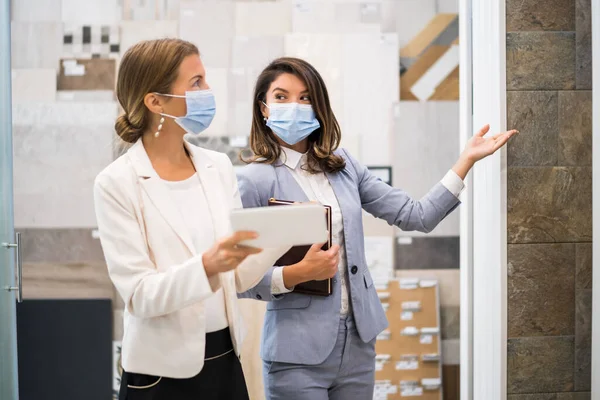 Küçük bir banyo dükkanı olan bir iş kadını. Malları seçen bir müşteriyle konuşuyor. Koruyucu yüz maskesi takıyorlar..