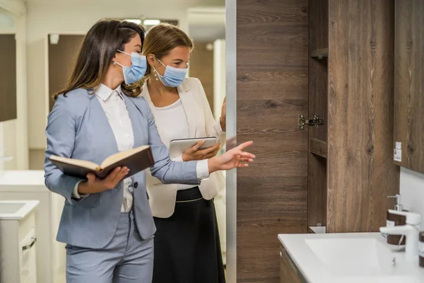 Küçük bir banyo dükkanı olan bir iş kadını. Malları seçen bir müşteriyle konuşuyor. Koruyucu yüz maskesi takıyorlar..