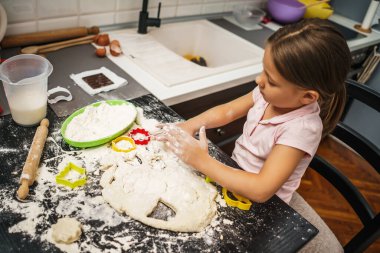 Küçük kız hamurla oynuyor, mutfakta kurabiye yapıyor..